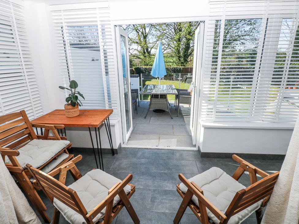 A conservatory with wooden chairs and a plant at Moonraker in Saundersfoot