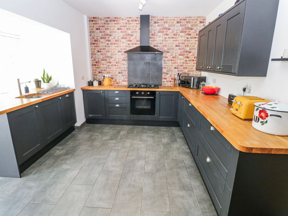A kitchen with cabinets, stove, and sink at Moonraker in Saundersfoot