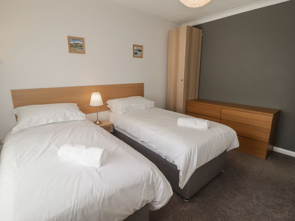 A bedroom with two single beds and a wardrobe at Moonraker in Saundersfoot