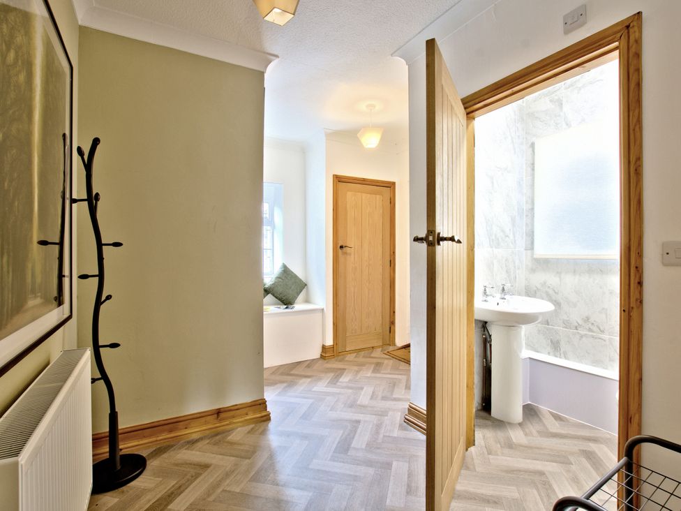 A hallway leading to a bathroom with a sink and window at River View Cottage Hanlith near Malham