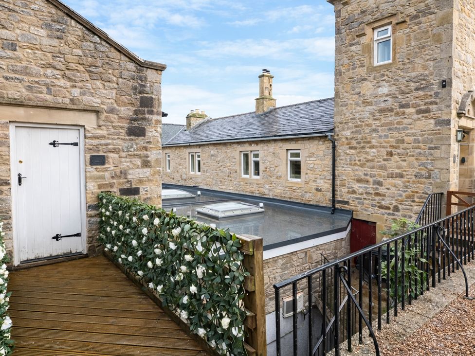 An outdoor view with stone buildings and a wooden deck at River View Cottage Hanlith near Malham