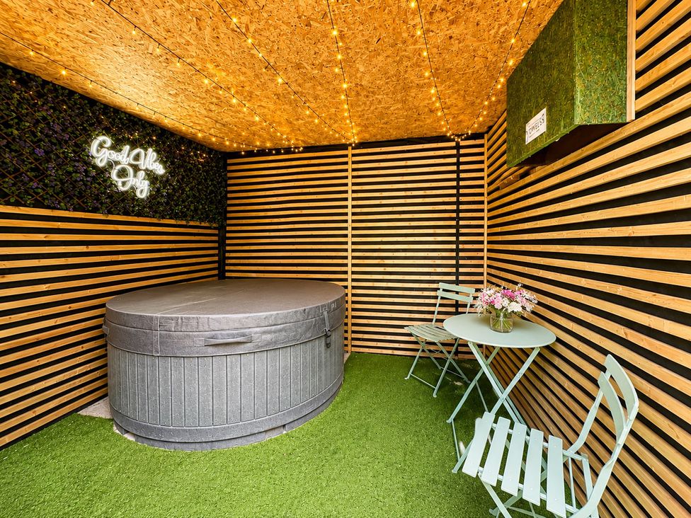 An outdoor seating area with a hot tub and a table at River View Cottage Hanlith near Malham