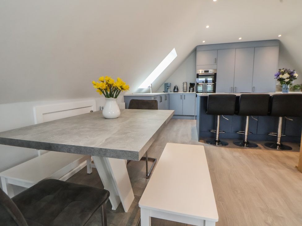 A kitchen with a table and bar stools at Mike’s Place in Rhyl