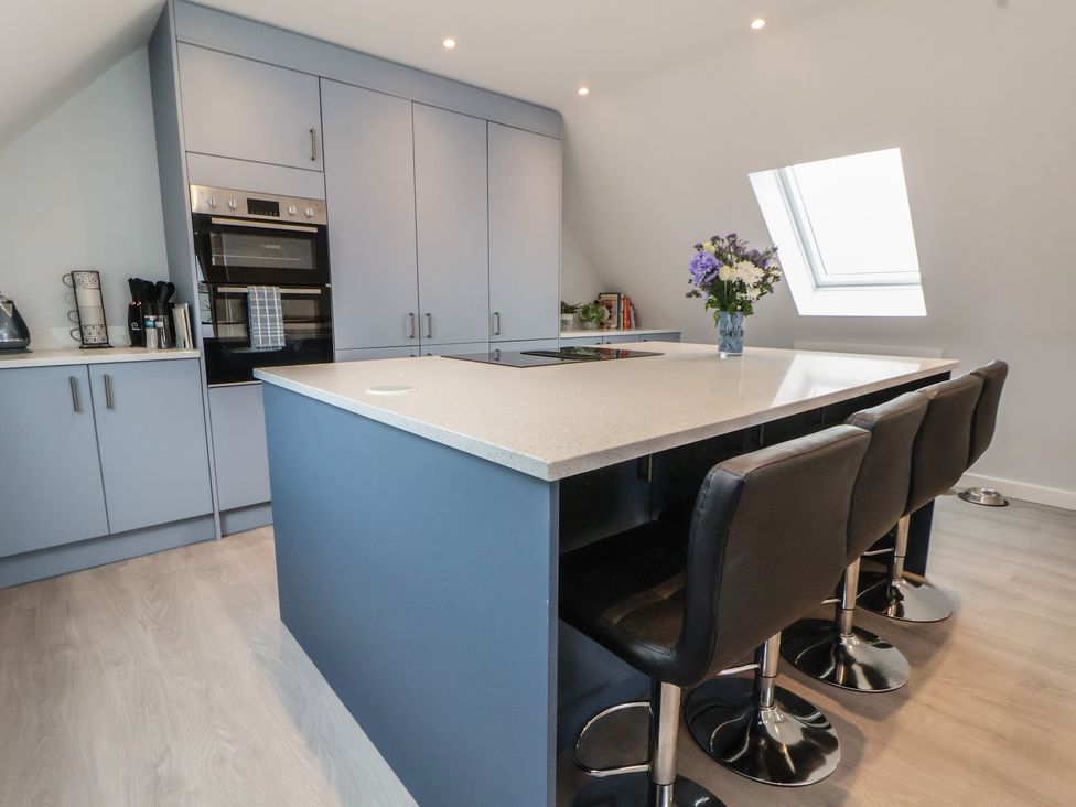 A kitchen with a kitchen island and stools at Mike’s Place in Rhyl