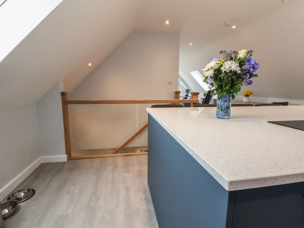 A kitchen with a blue island and a vase of flowers at Mike’s Place in Rhyl