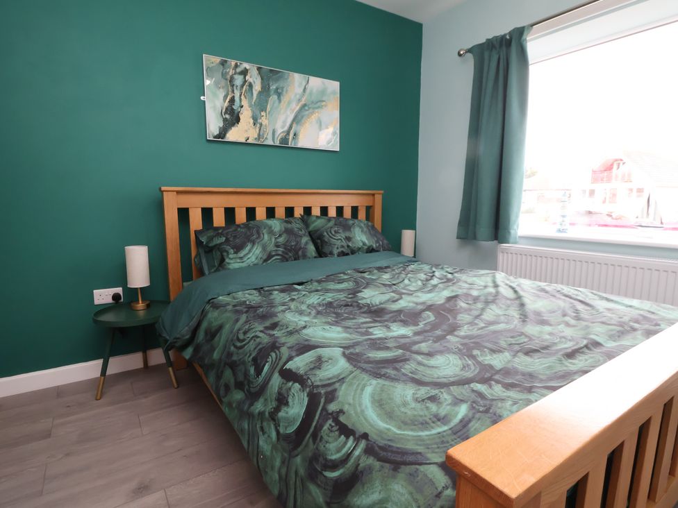 A bedroom with a bed and lamp at Mike’s Place in Rhyl