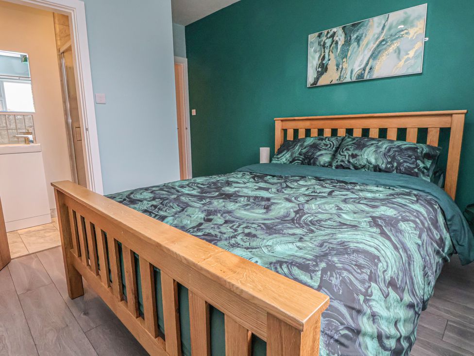 A bedroom with a wooden bed and bathroom door at Mike’s Place in Rhyl