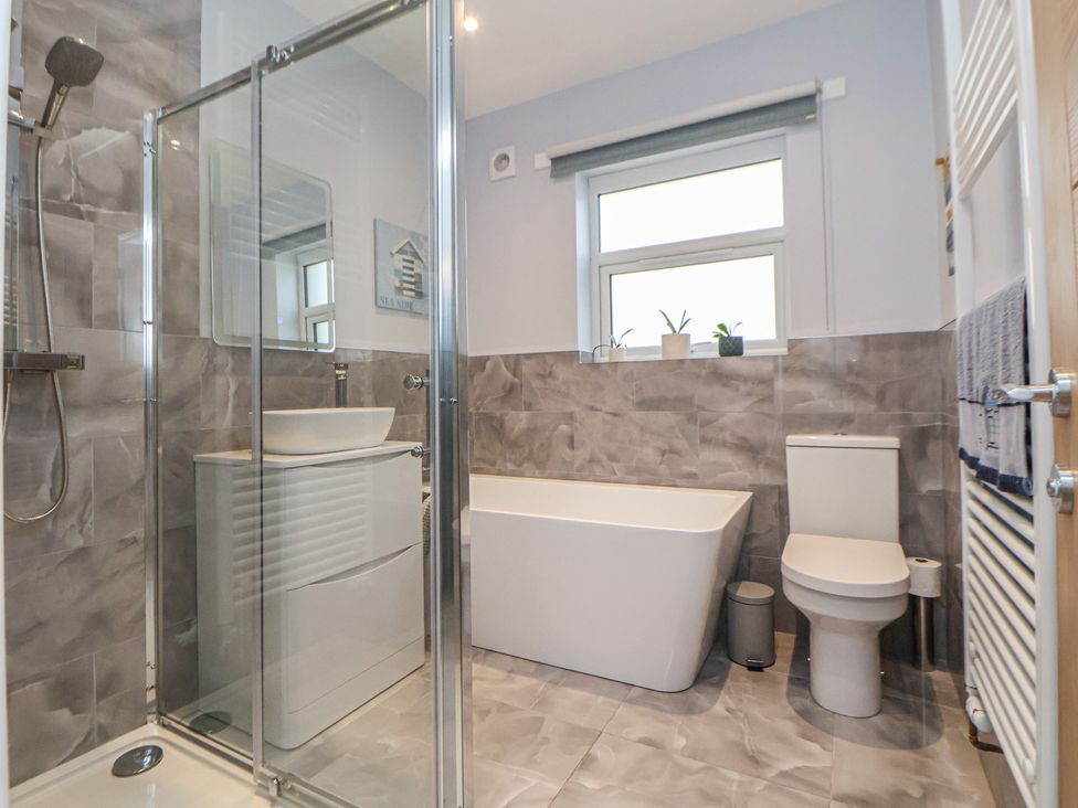 A bathroom with a shower, bathtub, toilet and sink at Mike’s Place in Rhyl
