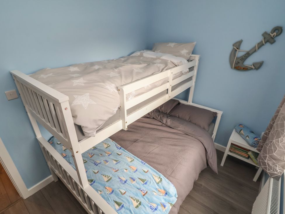 A bunk bed and nightstand in a bedroom at Mike’s Place in Rhyl
