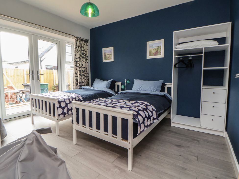 A bedroom with two single beds and a wardrobe at Mike’s Place in Rhyl