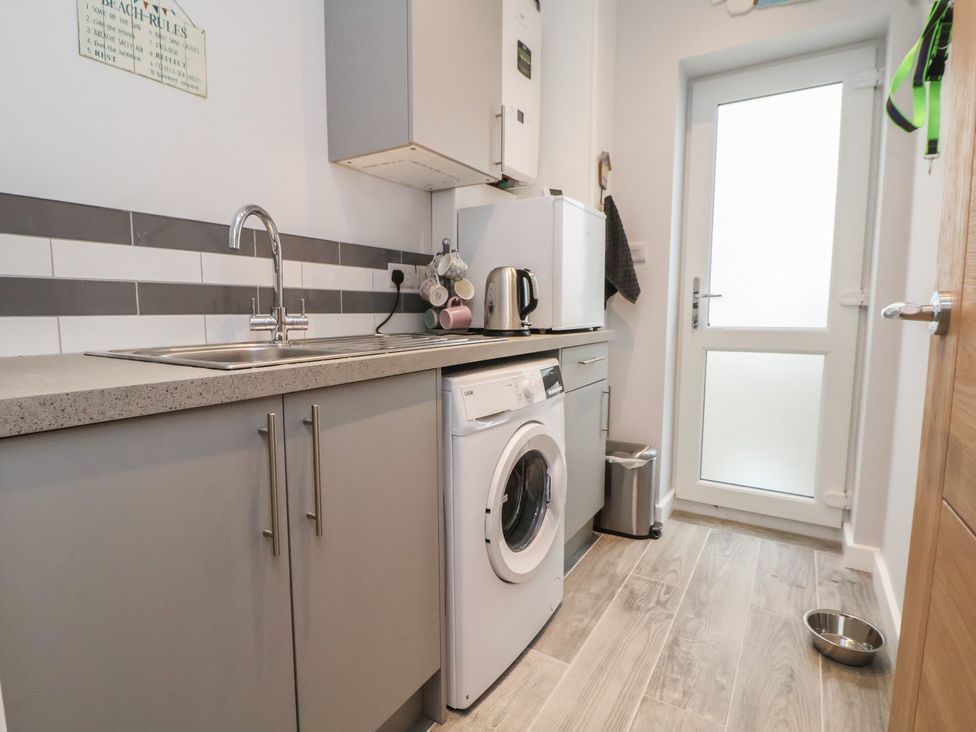 A kitchen with a sink, washing machine, and fridge at Mike’s Place in Rhyl