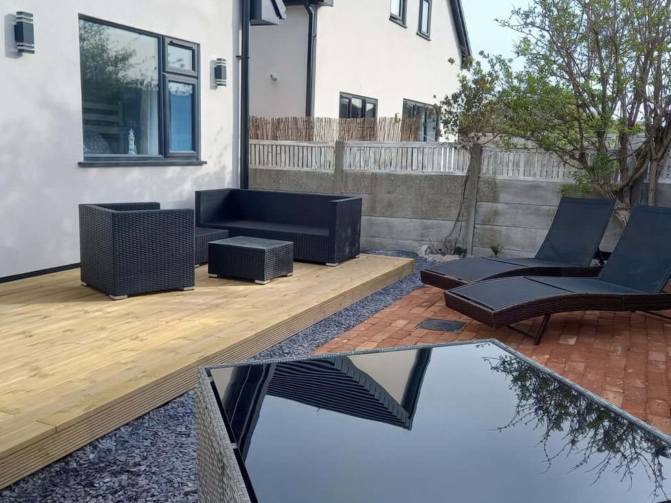 An outdoor seating area with a sofa and loungers at Mike’s Place On The Cove Rhyl