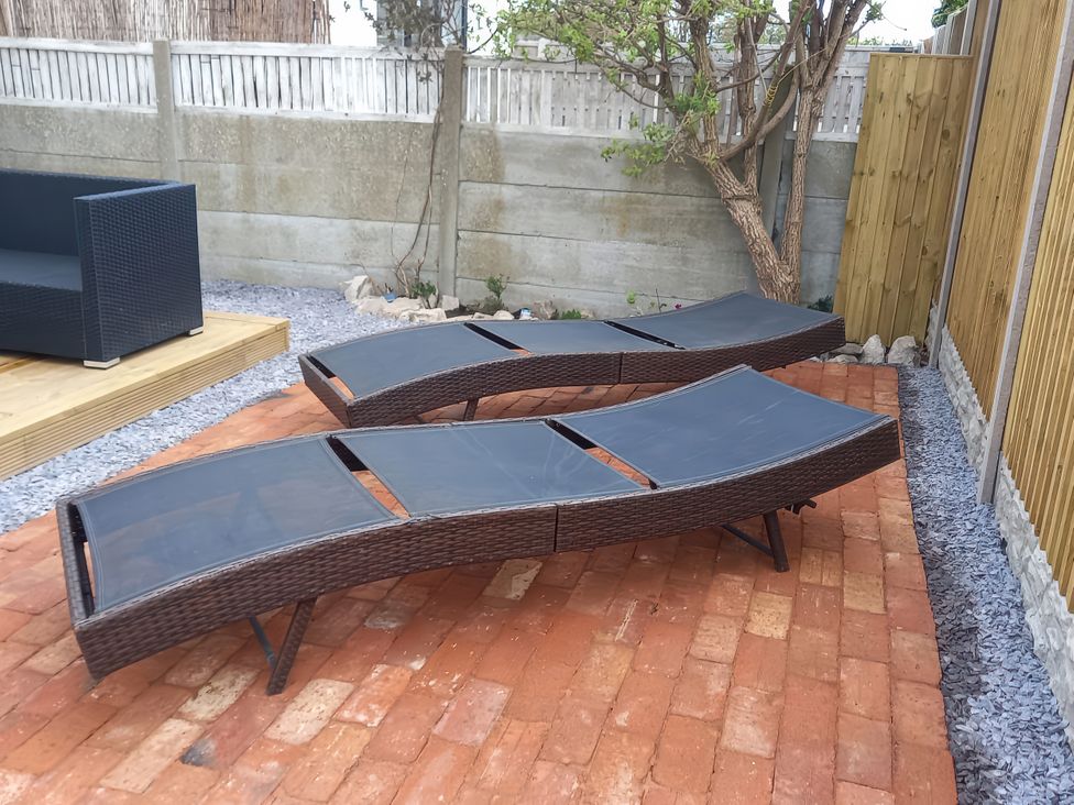 A garden with two sun loungers and an outdoor sofa at Mike’s Place On The Cove Rhyl