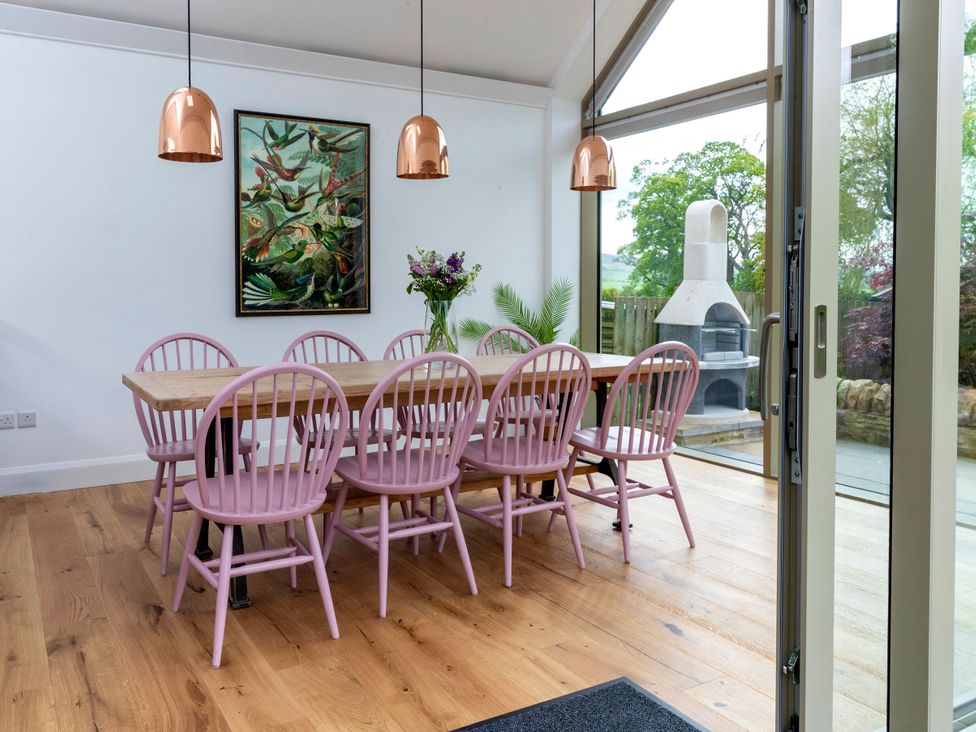 A dining room with a large table and pink chairs at 2 The Croft in Skipton