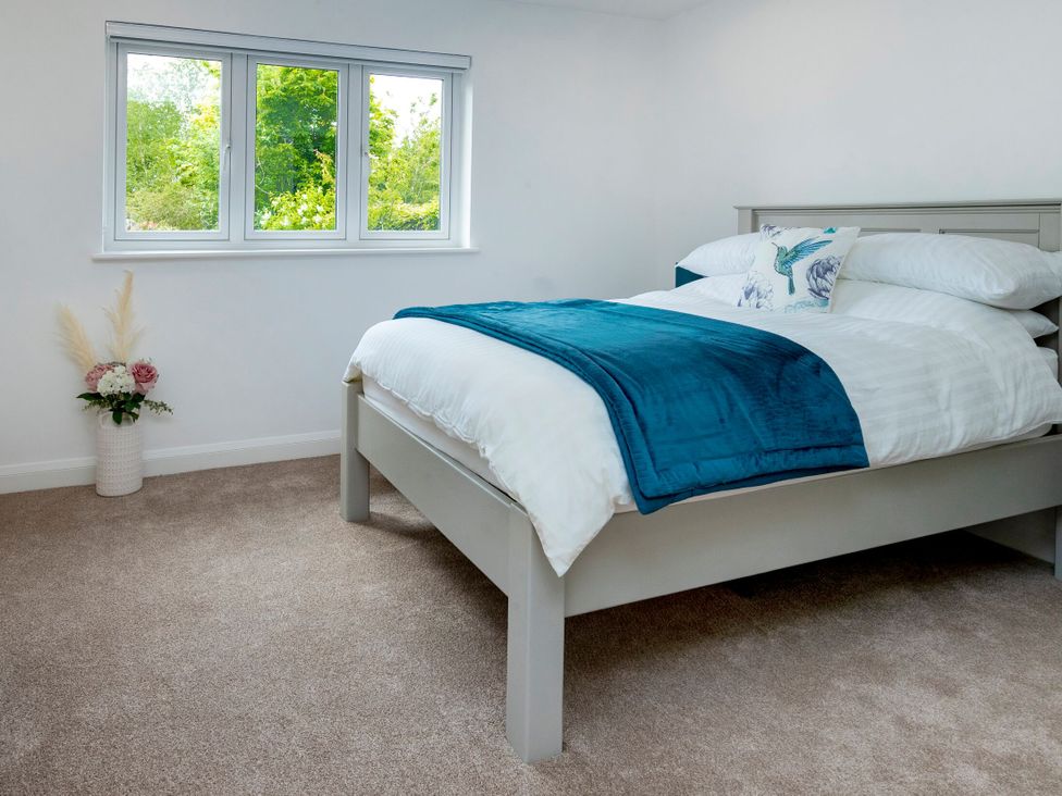 A bedroom with a bed and windows at 2 The Croft in Skipton