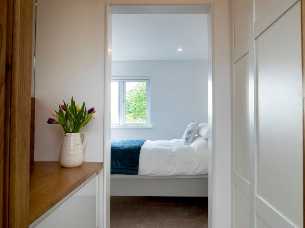 A bedroom with a view of a bed and a vase of flowers at 2 The Croft in Skipton