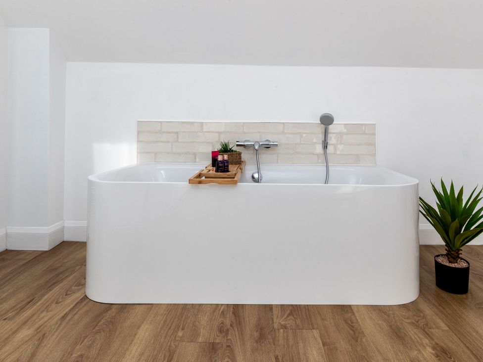 A bathtub with a wooden tray and plants at 2 The Croft in Skipton