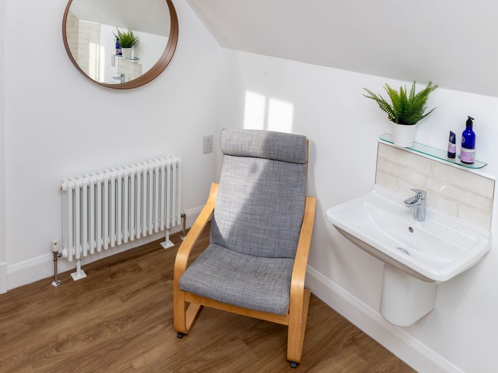 A bathroom with a chair and sink at 2 The Croft in Skipton