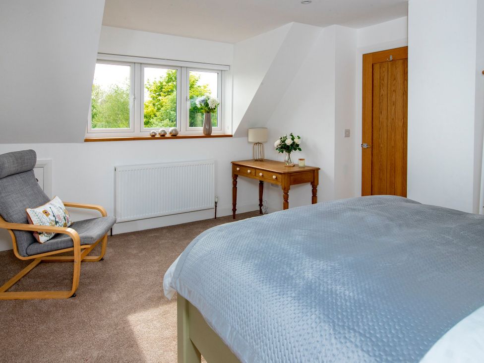 A bedroom with a bed, armchair, and table at 2 The Croft in Skipton