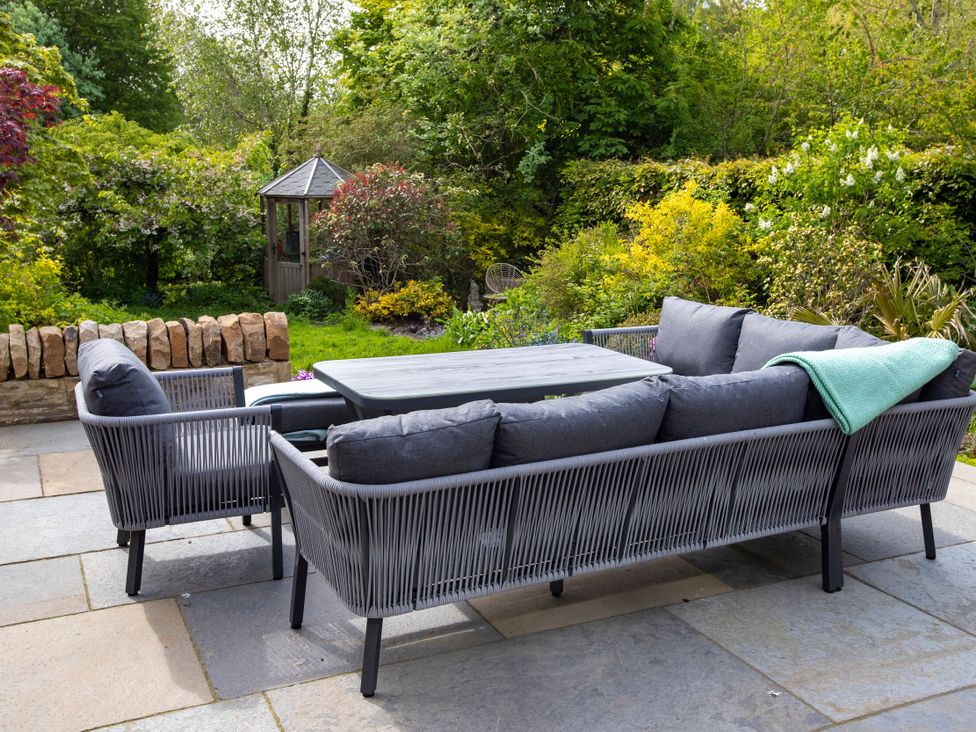 A garden with seating area featuring a sofa and table at 2 The Croft in Skipton
