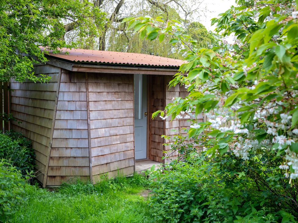 A wooden shed with a door and plants at 2 The Croft in Skipton
