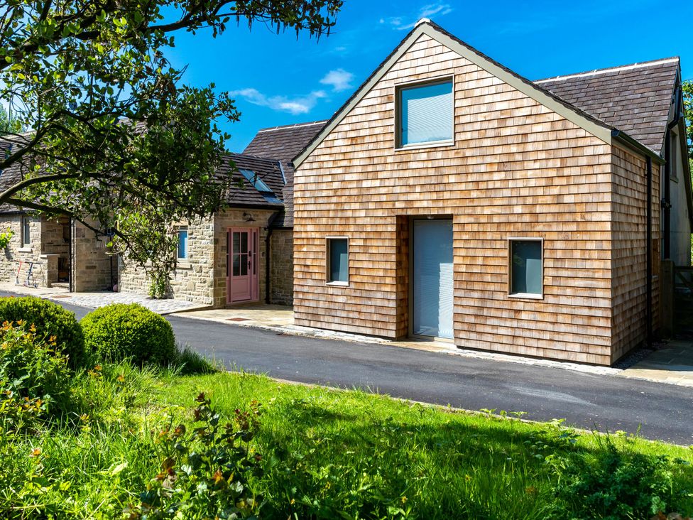 A house exterior with wooden siding and a pathway at 2 The Croft Skipton