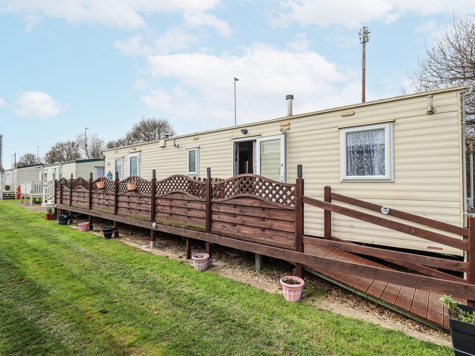 An outdoor area with a mobile home and wooden deck with fence at The Promenade in Skegness