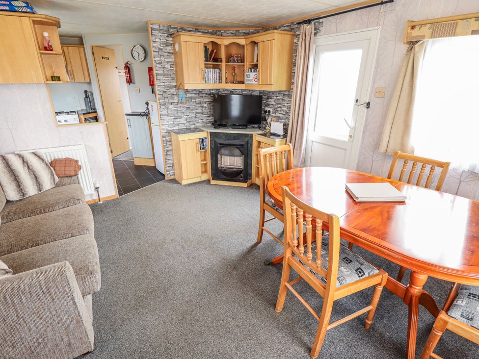A living room with a sofa, dining table, and television at The Promenade in Skegness