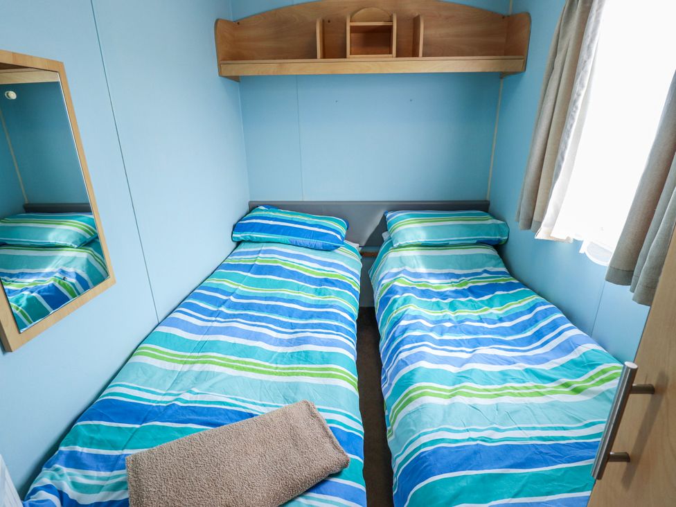 A bedroom with twin beds and a mirror at The Promenade in Skegness