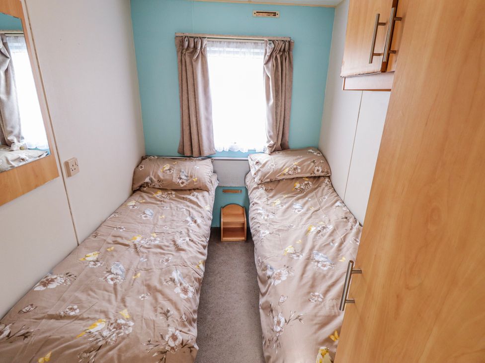 A bedroom with two beds and a mirror at The Promenade in Skegness