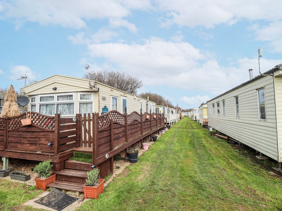 A row of mobile homes with a pathway and potted plants at The Promenade in Skegness