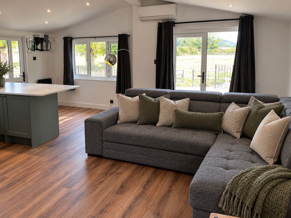 A living room with a sofa and kitchen island at Meadow View Cottage in Gloucester