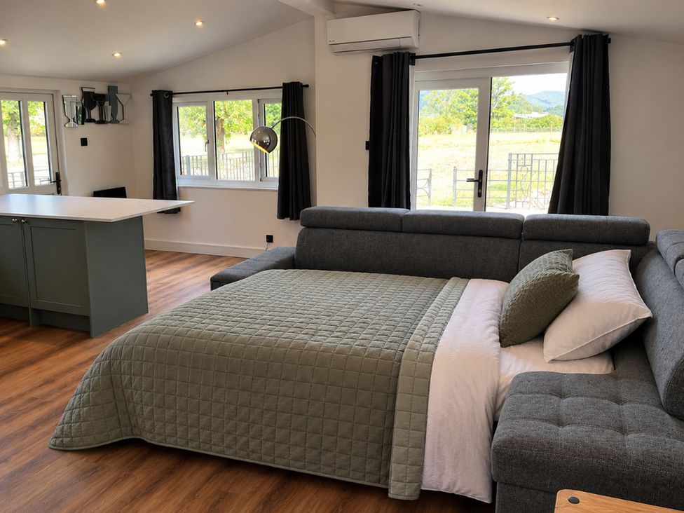 A living room with a sofa and kitchen island at Meadow View Cottage in Gloucester