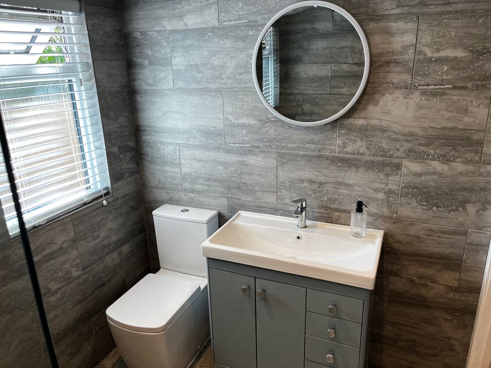 A bathroom with a sink, toilet, and mirror at Meadow View Cottage in Gloucester