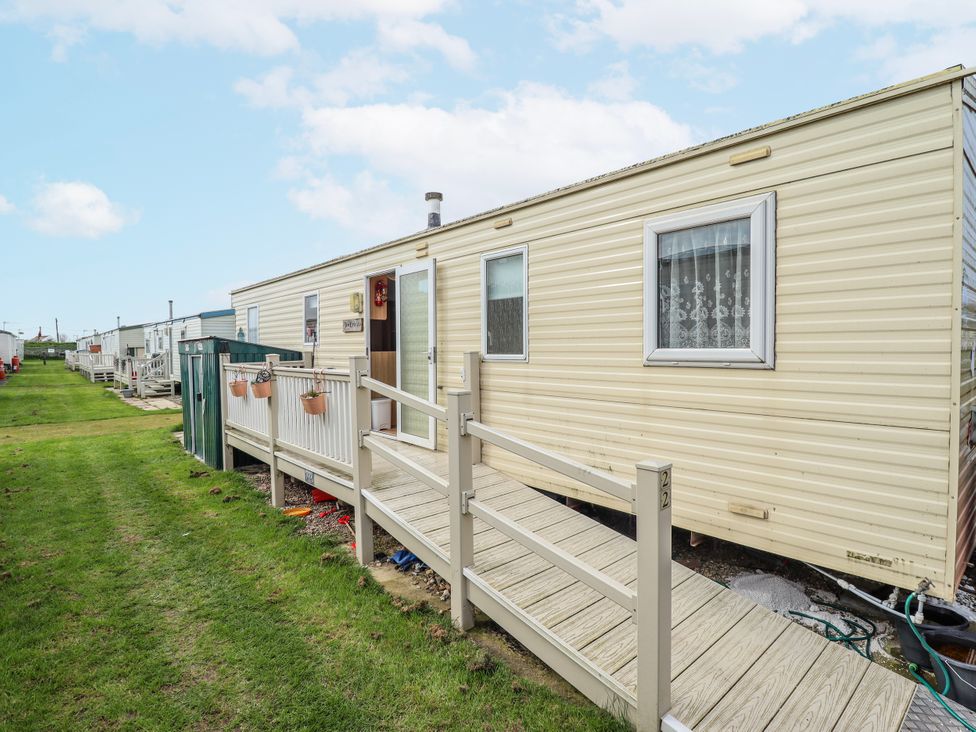 A mobile home with a wooden deck and steps at Seaview in Skegness