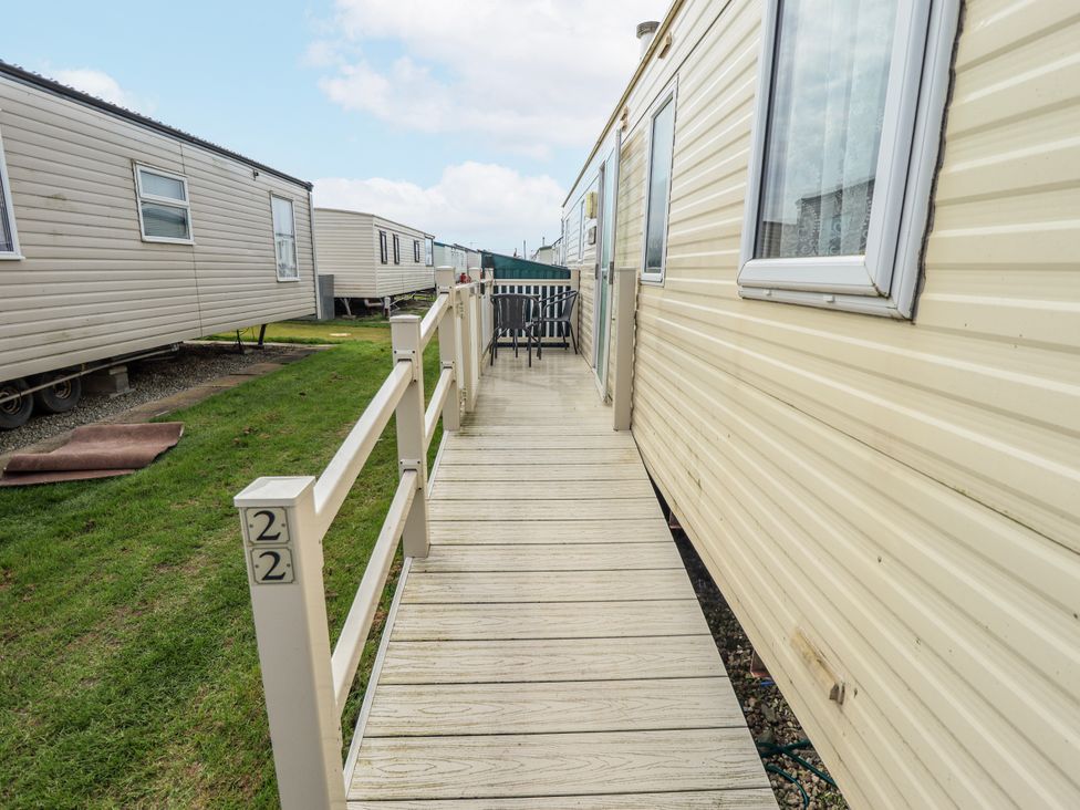 A deck area with a table and chair near a trailer at Seaview in Skegness