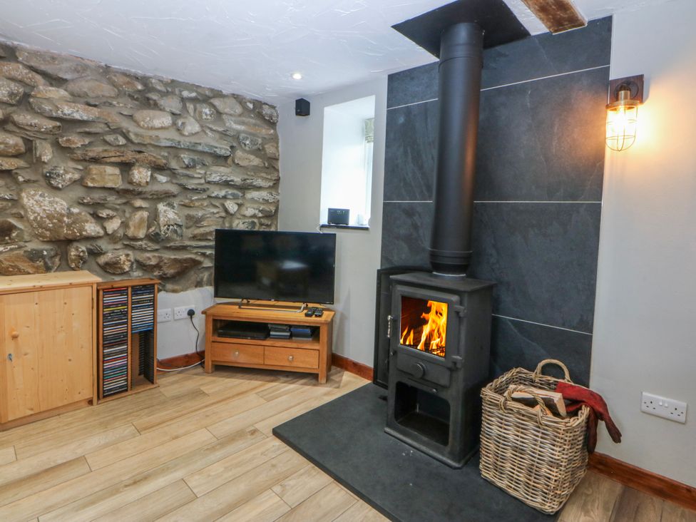 A living room with a fireplace and television at Little Barn near Criccieth