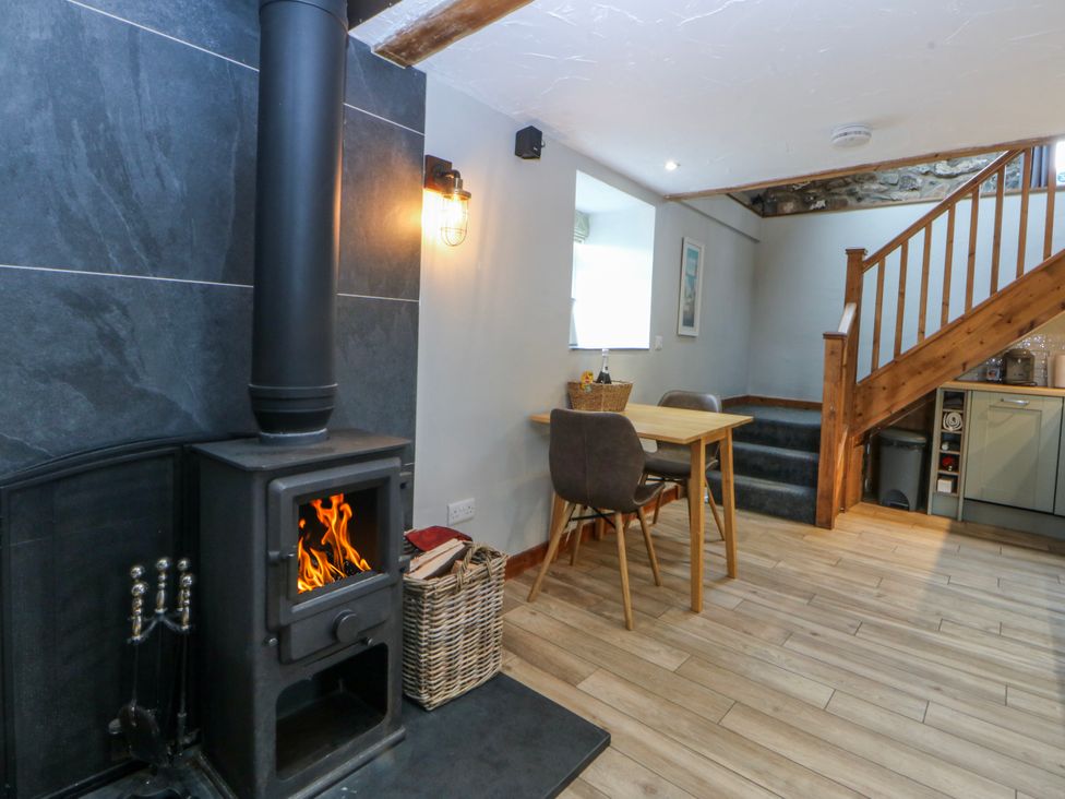 A living room with a wood stove and a dining table at Little Barn near Criccieth