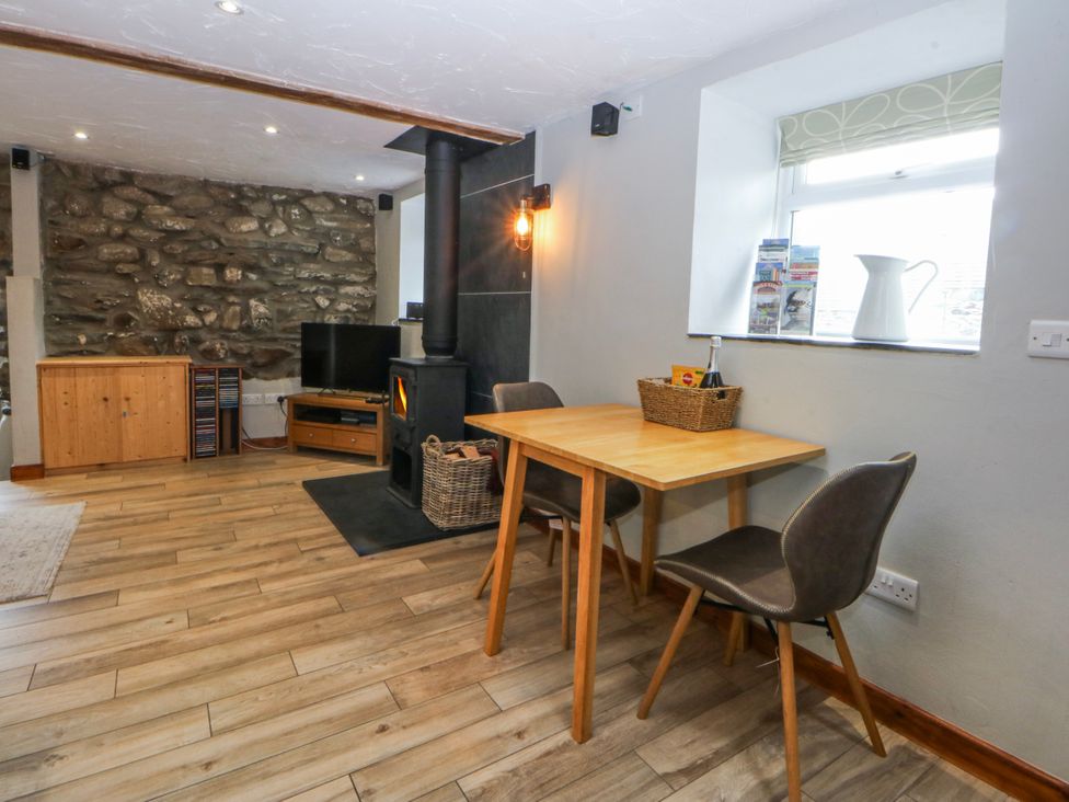 A dining room with a table and stove at Little Barn near Criccieth