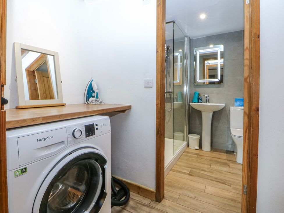 A laundry room with a washing machine and a shower at Little Barn near Criccieth