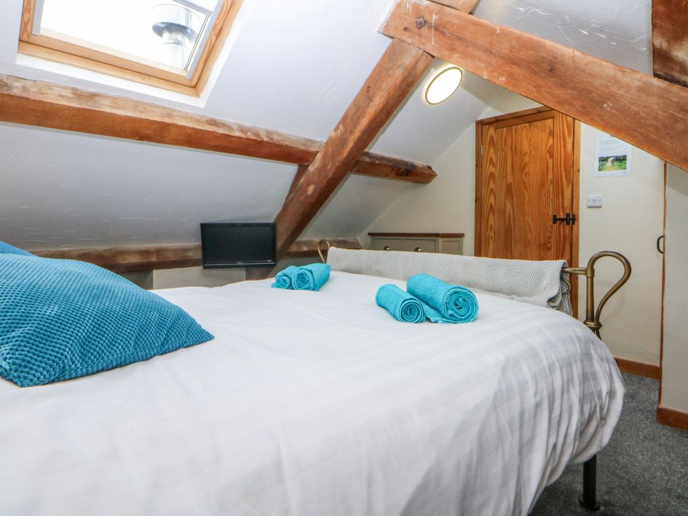 A bedroom with a bed and towels at Little Barn near Criccieth