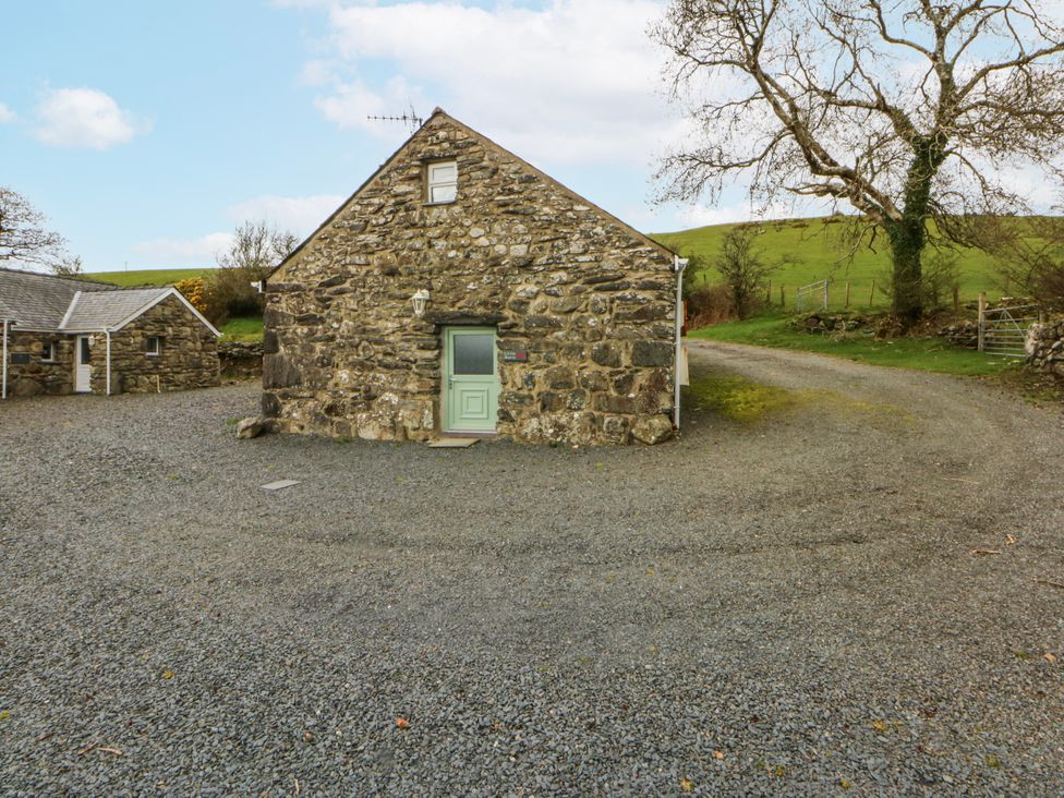 A stone cottage with a gravel driveway at Little Barn near Criccieth