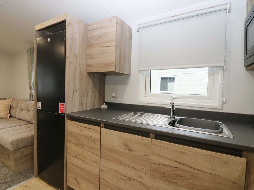A kitchen with a fridge, sink, and cabinets at 63 St Andrews in Prestonpans