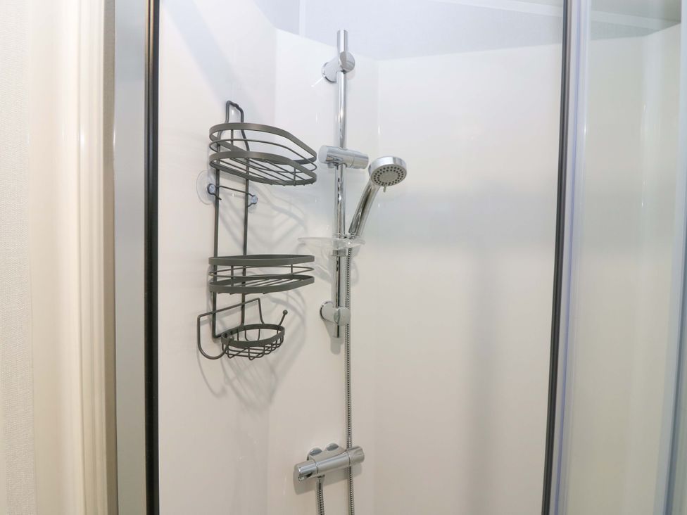A shower with a showerhead and storage baskets at 63 St Andrews in Prestonpans