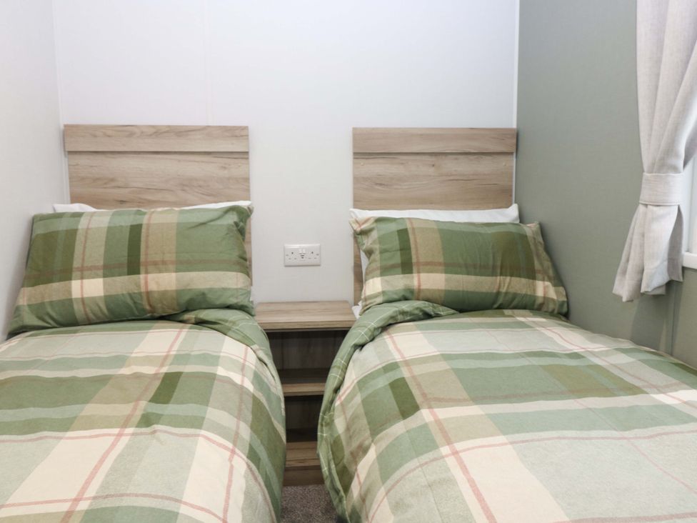 A bedroom with two beds and a bedside table at 63 St Andrews in Prestonpans