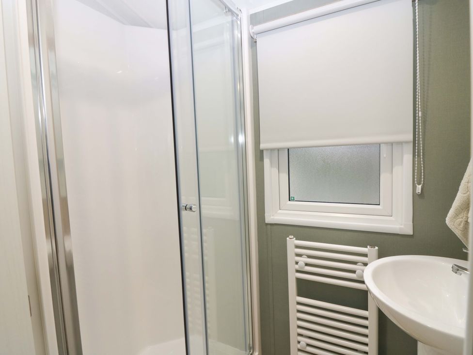 A bathroom featuring a shower, sink, and towel radiator at 63 St Andrews, Prestonpans