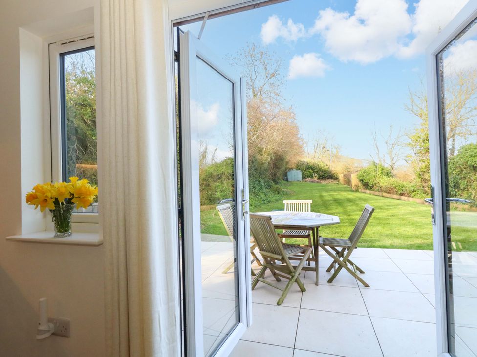 A dining area with a table and chairs overlooking a garden at The Pebble in Dorchester