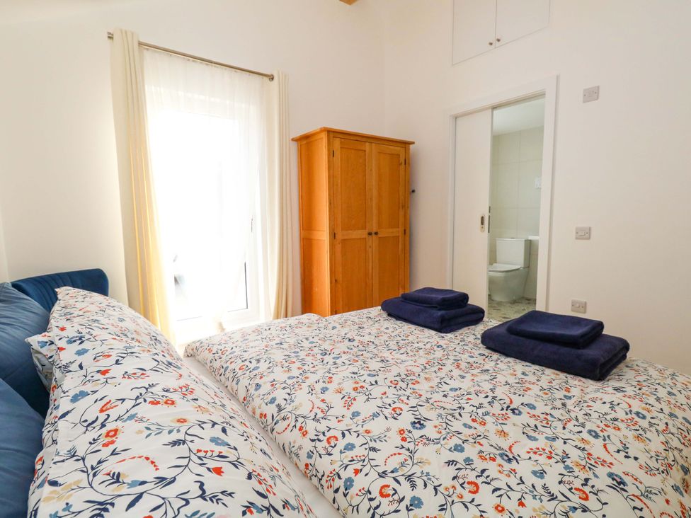 A bedroom with a bed, wardrobe, and towels at The Pebble in Dorchester