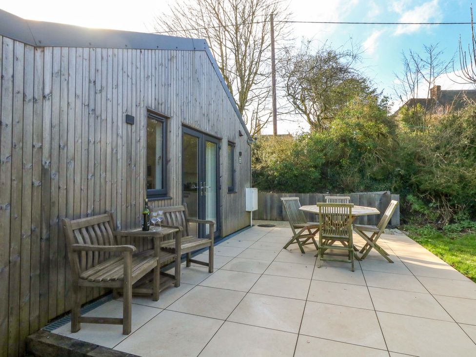 A garden patio with wooden furniture at The Pebble in Dorchester