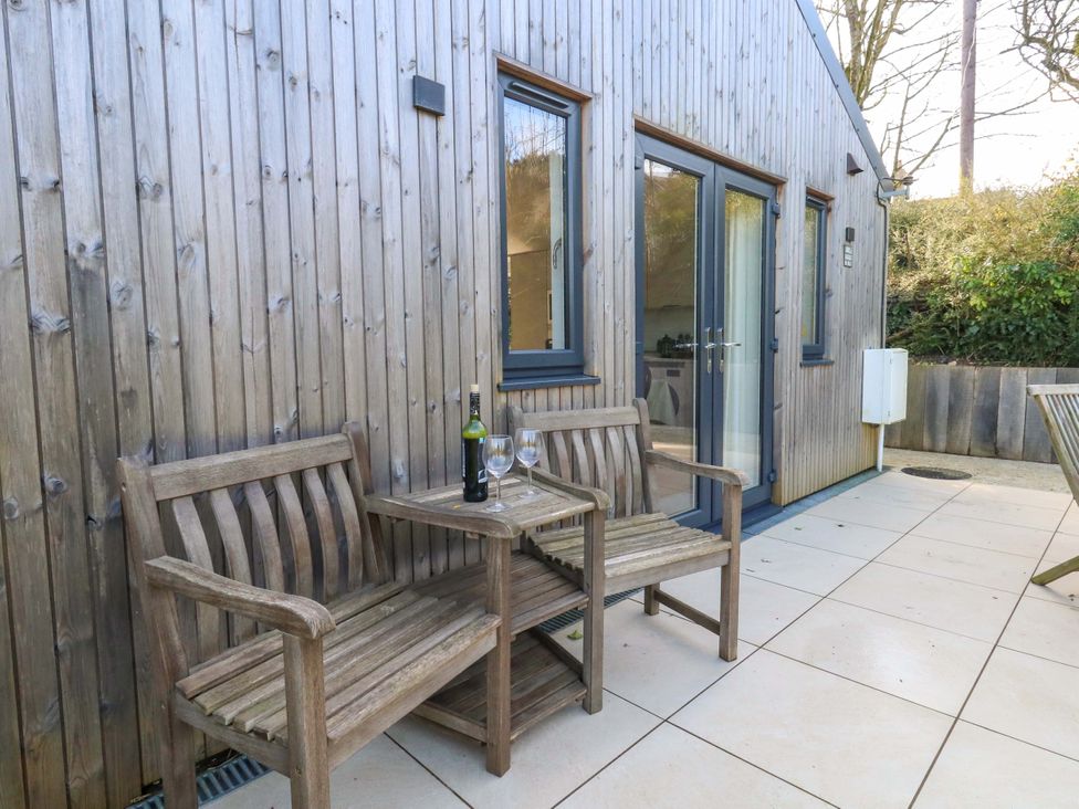 An outdoor patio with wooden benches and wine glasses at The Pebble in Dorchester